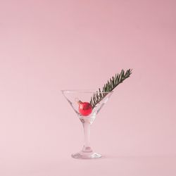 Christmas tree decoration in martini glass on pastel pink background with creative copy space
