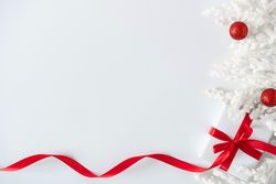 Gift box wrapped with red ribbons, and decorations, on light background