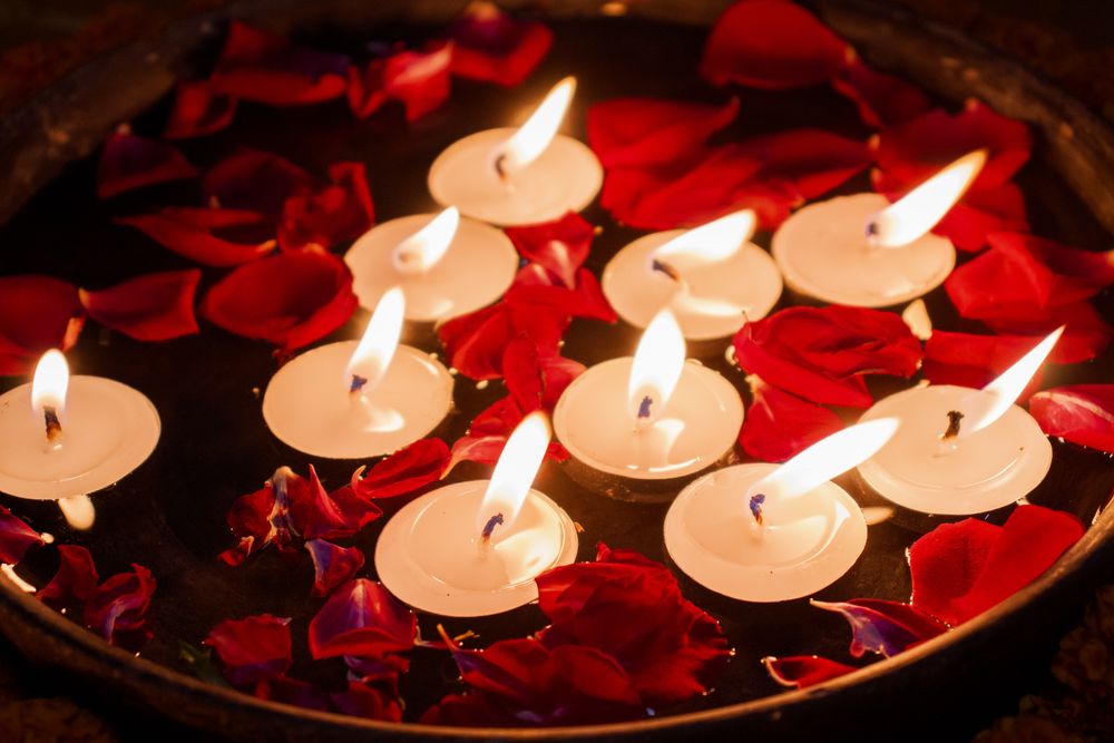 Candles in red rose bowl in dark room