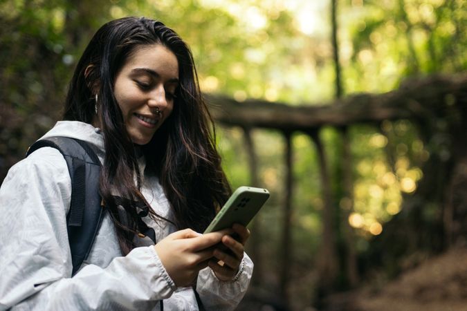 Young woman texting in the forest