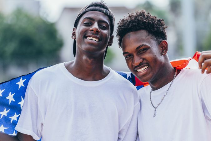 Black men wrapped in American Flag outside