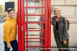 Male and female posing on different sides of a phone booth 0K1QM4
