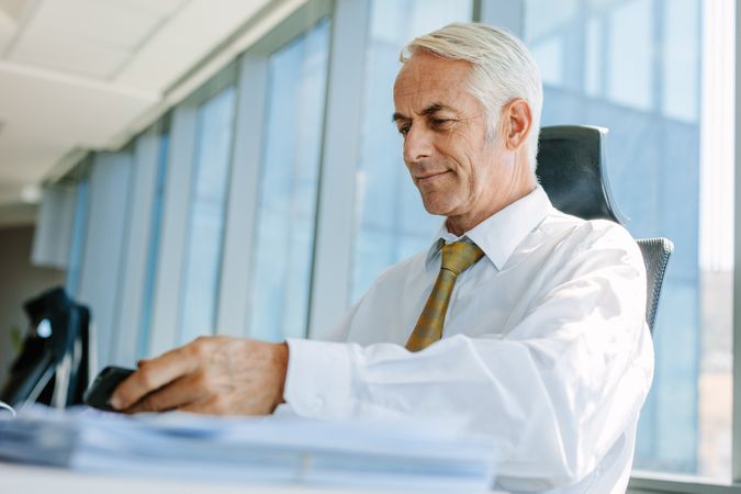 Older male manager sitting at his desk and working