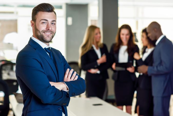 Male business leader standing in foreground of busy office