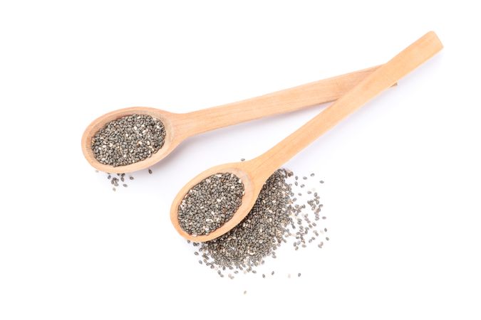 Chia seeds and wooden spoons isolated on plain background