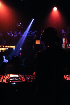 Back view of man DJing in dark club