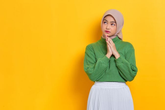 Woman in headscarf pondering something with the palms of her hands together