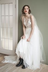 Adult confident woman in white dress and military shoes leaning on wall