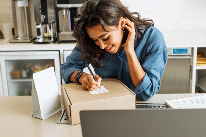 Woman in bright cafe with a box for shipment