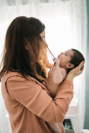 Mom holding newborn on hands at home