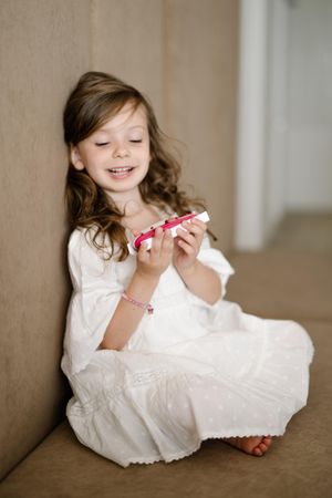 Girl in light dress smiling and holding a toy