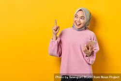 Excited Muslim woman on the phone and pointing upwards holding smart phone 49QDB4