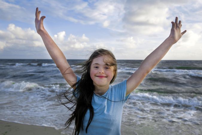 Happy child throwing arms up in the air at the beach