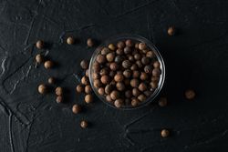 Top view of glass bowl with peppercorns on dark background