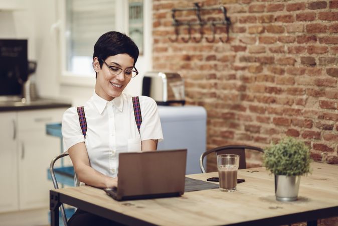 Smiling woman in loft apartment working on computer at table