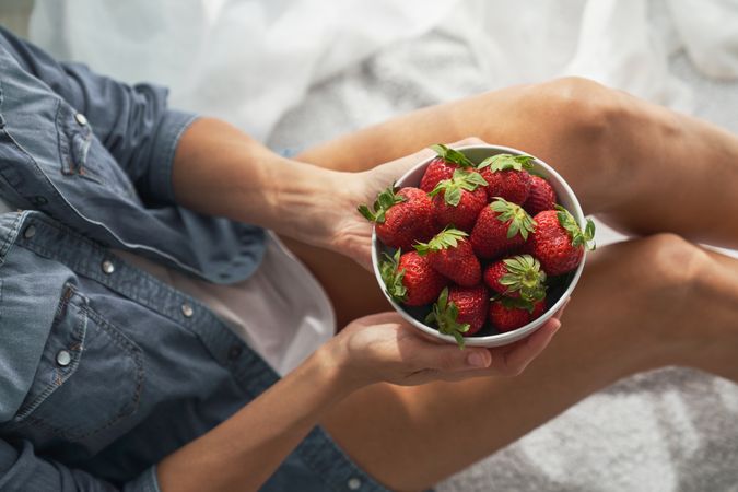 Faceless woman with bowl of tasty strawberries in hands