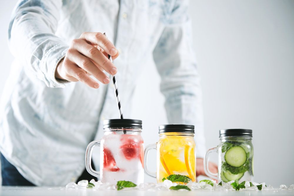 Man putting straw into glass jar of fruit infused water