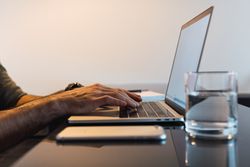 Faceless man typing on laptop