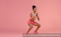 Sporty woman practicing squat exercises in studio 4O67R5