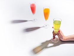 Hand and glasses of bright colorful drinks on table