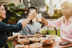Happy people eating and cheering at food truck restaurant - Focus on girl hand holding cup of drink