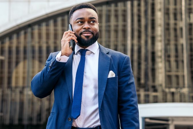 Business Black man in suit talking on the phone while leaving the office