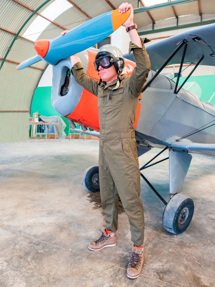 Confident pilot beside retro plane in hangar
