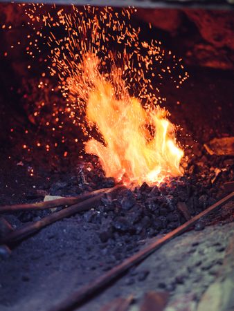 Unrecognizable blacksmith burning metal in furnace