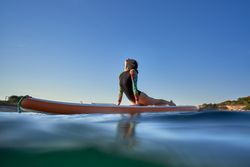 Slim woman practicing yoga in Bhujangasana on paddleboard