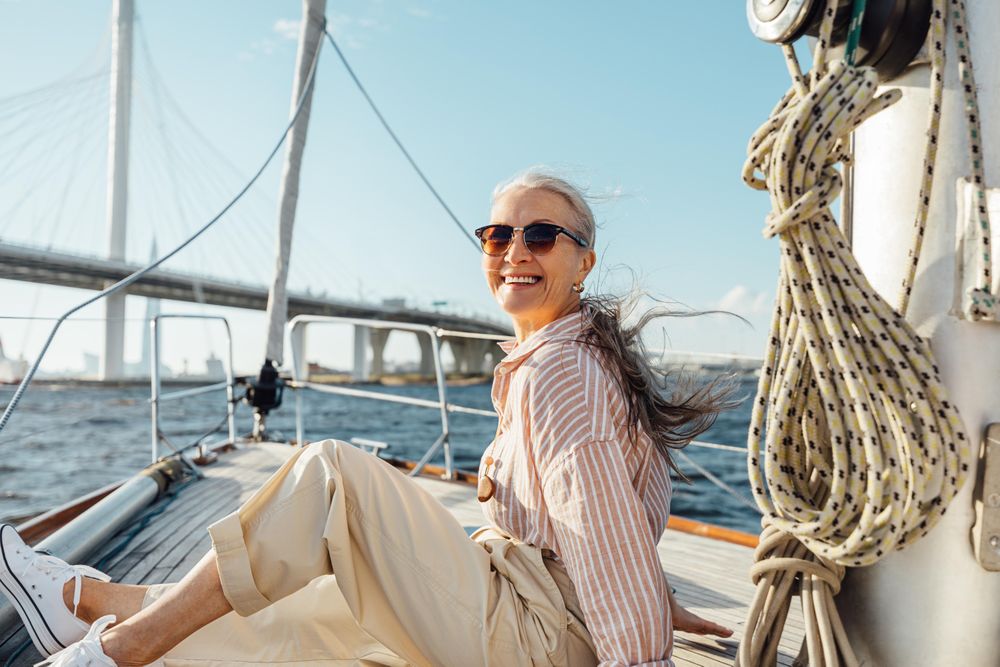 Stylish mature woman sitting on a yacht bow with bridge in background