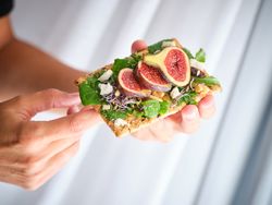 Crop person with figs on crisp bread