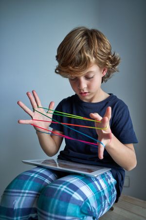 Focused boy browsing tablet while playing string game