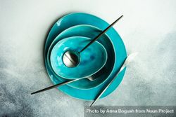 Top view of full teal table setting & silverware with on grey background bGRxrY