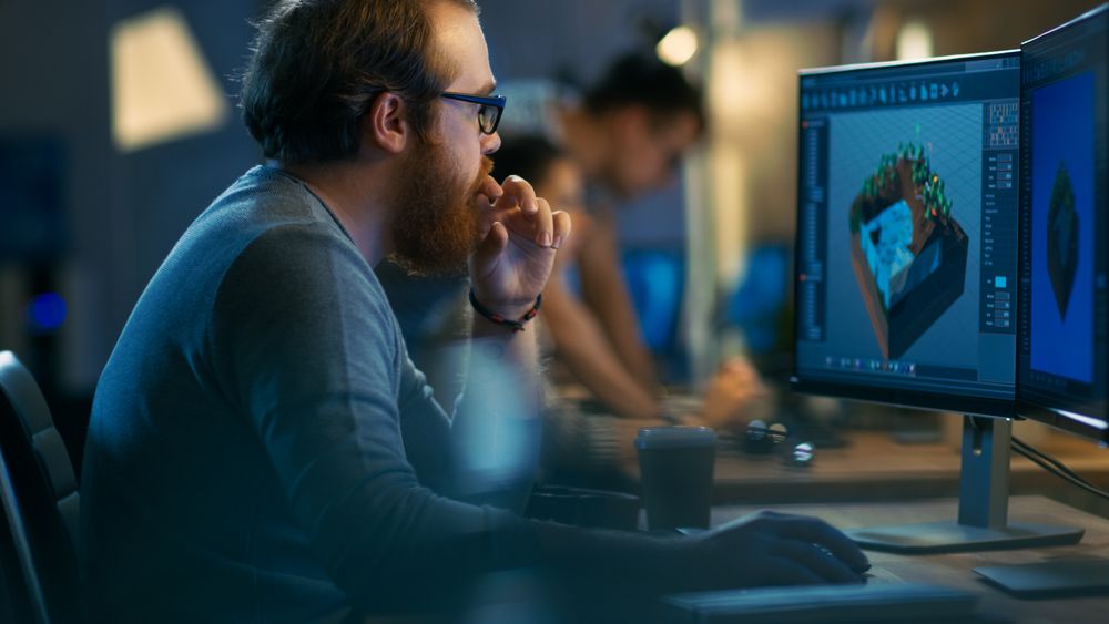 Male Game Developer works on a Level Design on His Personal Computer with Two Displays.