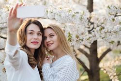 Friends taking selfie near blooming trees