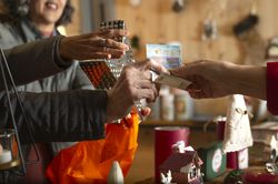 Crop woman with unrecognizable friend and shop owner making cash transaction