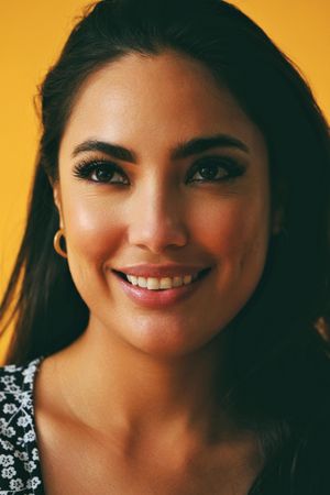 Headshot of smiling Hispanic woman in yellow room, vertical