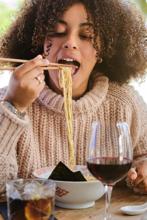 Black female eating ramen in restaurant
