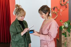 Delighted woman paying for skin care treatment with smartphone on POS terminal