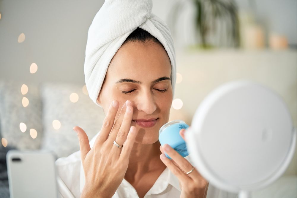 Relaxed woman applying cream on face while taking video