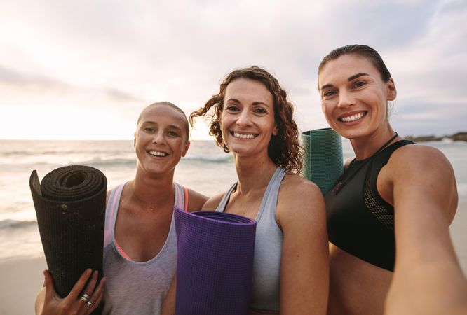 Group of yoga friends standing at the beach
