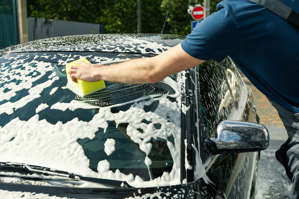 Man wipes the car with a sponge. Car wash. Clear car concept