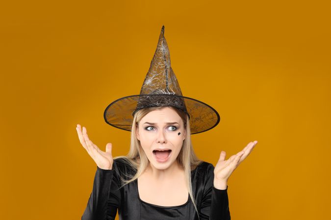 Concept of Halloween, young woman on yellow background