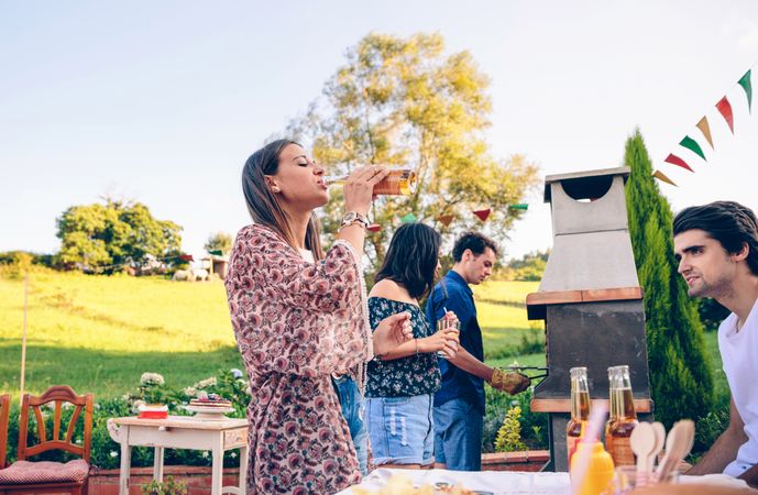 Woman drinking beer at a barbecue with friends
