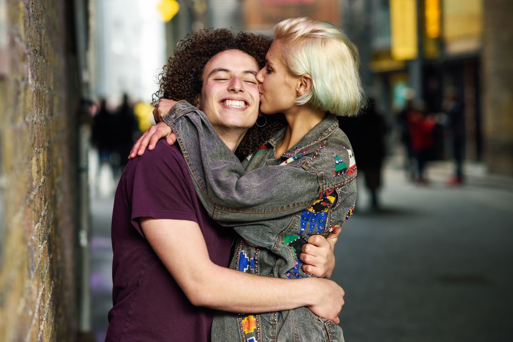 Woman kissing and hugging her boyfriend on British city street