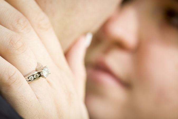 Female Hand with Engagement Ring Touching Fiance's Face