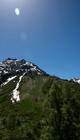 Rocky mountain slope with snow patches and waterfalls