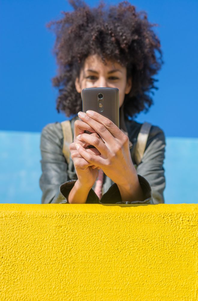 Black woman with afro hair leaning against brightly colored wall