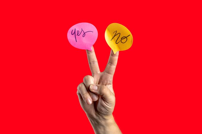 Hand making V-sign with "yes" and "no" speech bubbles on red background.