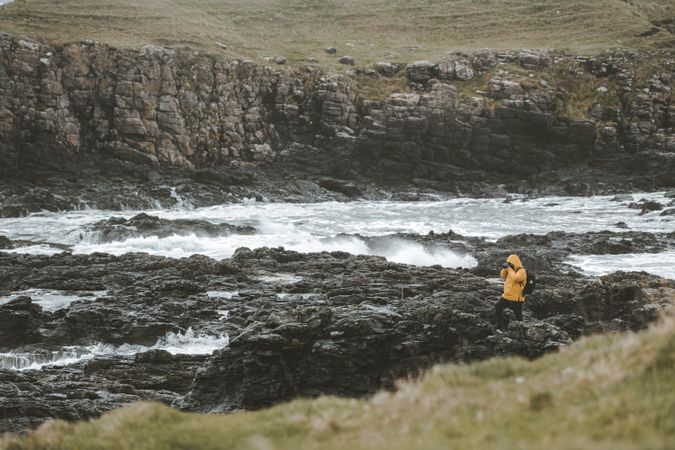Man standing on rock and taking picture of sea